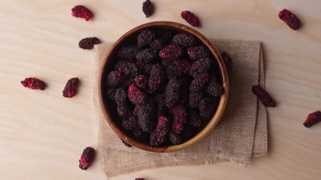 Dried black mulberries on a bowl closeup.