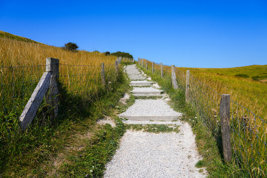 Gravel hiking path with wooden steps climbing towards the Dover Patrol Monument obelisk on Cap Blanc-Nez, France