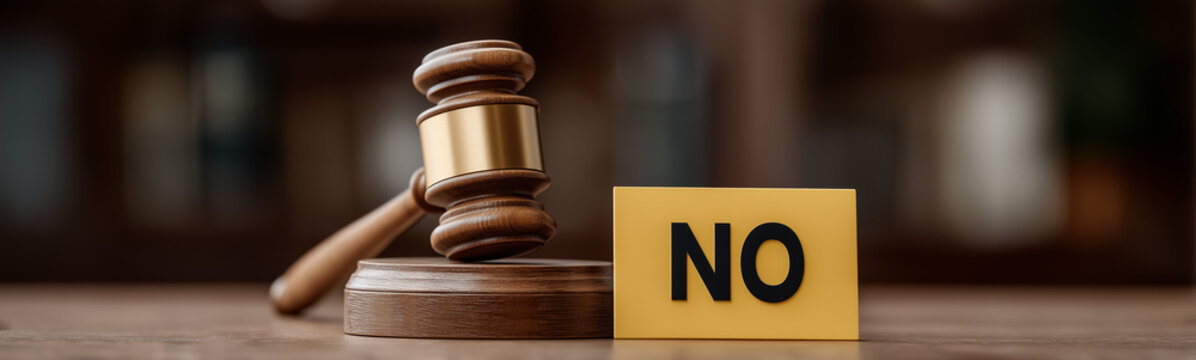 Gavel and the Decision: A gavel rests on its block beside a block displaying the word 'NO', symbolizing a definitive choice or legal ruling, set against a blurred background.