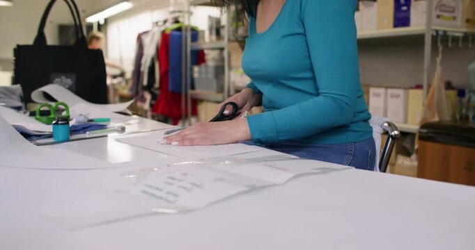 Tailor cutting. Fashion creation. Designer making paper pattern with professional tailor tool. Woman measuring draft model with curve ruler.