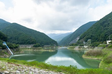 Fototapeta premium 埼玉県飯能市にある名栗湖（有間ダム）の山々に囲まれた穏やかな水面/Calm Water Surface of Lake Naguri Surrounded by Mountains
