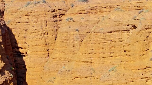 Aerial view captures majestic eroded sandstone mountains in Konorchek canyons. Sparse desert vegetation complements serene desert landscape under bright daylight.