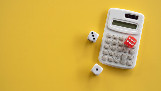 Red and White Dice Scattered Around White Electronic Calculator on Yellow Background
