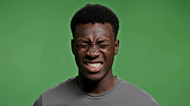 Portrait of a young man with serious expression against green background