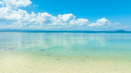 Fototapeta premium Tropical Nature clear sky and summer sea water under a clear blue sky with beautiful clouds and bright sunlight. Perfect for summer vacation and travel background 