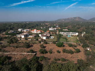 Obraz premium Stunning aerial view of a remote mountain village nestled in the hills, surrounded by beautifully layered terraced fields. The warm golden sunlight highlights the natural contours of the landscape.