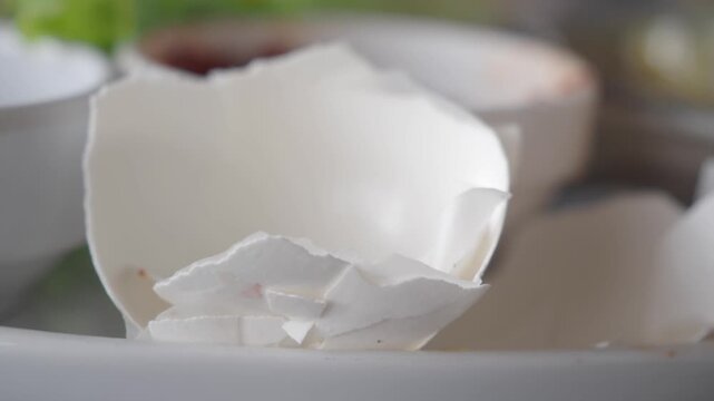 Broken white eggshell fragments on plate close up cinematic macro kitchen background clip.