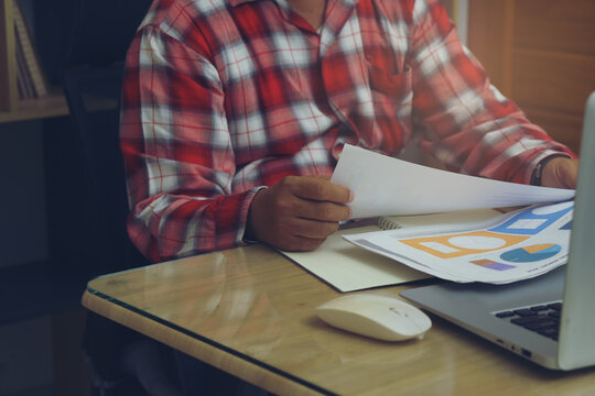 Businessman hand review and checklist annual report, summary report, and paper on office desk. Professional Accountant checking and planning financial data. Business man and planner concept.