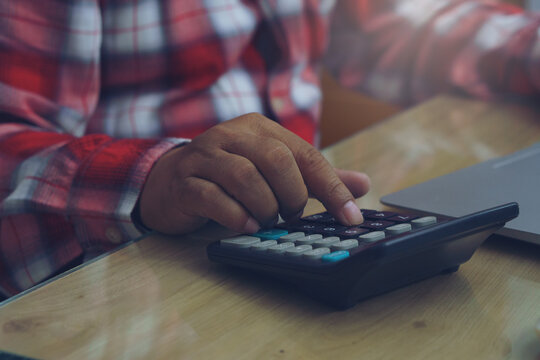 Business man hand planning and use caculator to calculate budget, work on laptop. Professional Businessman writing on paper and analysis annual report at home office. Business Concept.