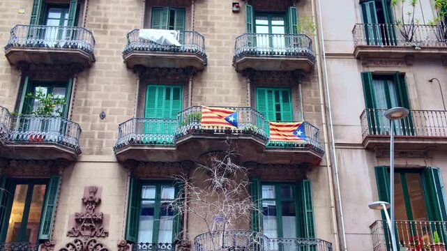 Two Estelada flags, a symbol of the Catalan independence movement, hanging from a balcony of a historic building in Barcelona, Spain