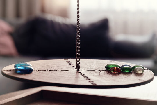 Dowsing pendulum on a wooden board with colorful glass stones