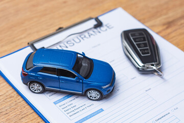Close up of automobile insurance application form with miniature car model and electronic keychain....
