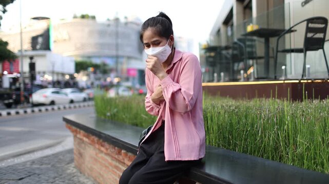 Person wearing mask in toxic urban air, monitoring pollution levels on device, highlighting health risks, environmental hazards, smog, and city pollution concerns.
