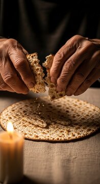 Hands breaking matzo for jewish seder.