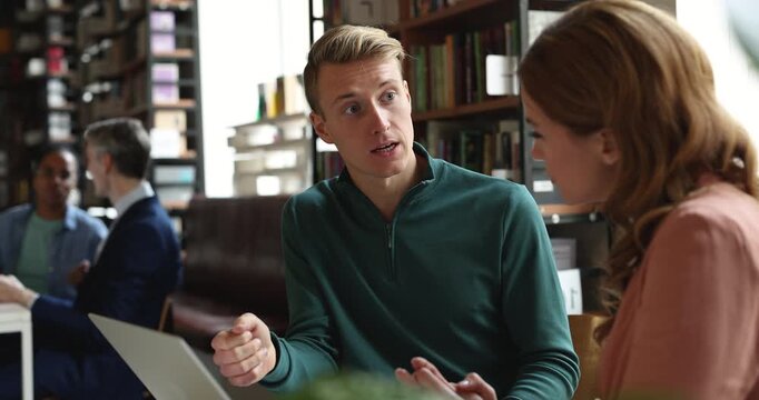 Two Caucasian colleagues discussing project details, analyzing information, sharing opinion, brainstorming ideas or solutions, making business decision during collaborative meeting, teamwork in office