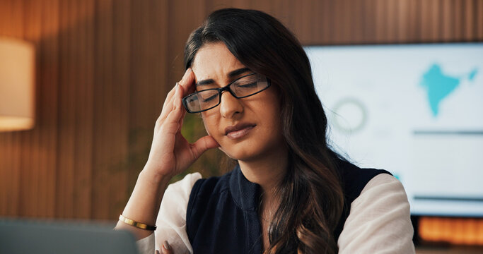 Frustrated, woman and headache with laptop in office for finance mistake, stats error and workload. Graphs, financial analyst and stress with tech for metrics inconsistency, migraine and overwhelmed