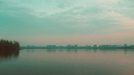 Naklejka premium Sunset over urban skyline reflected in calm water