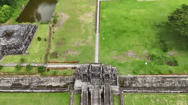 Drone flight over the majestic entrance gates of Candi Ratu Boko - Ancient heritage site on the hill, showcasing stone staircases and green lawns, Java, Indonesia.