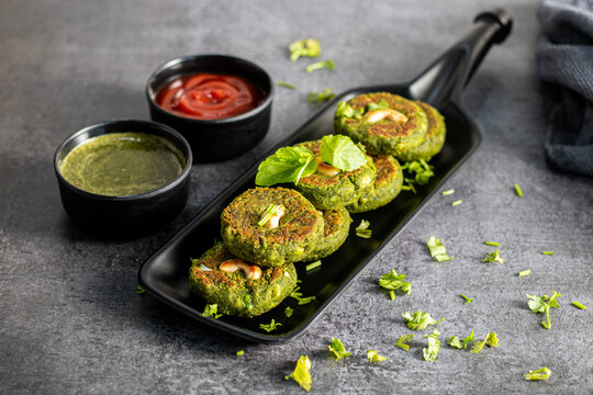 Crispy hara bhara kabab served with refreshing mint chutney and tangy tomato sauce, vibrant Indian vegetarian appetizer, delicious snack plating appealing presentation
