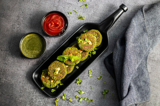 Crispy hara bhara kabab served with refreshing mint chutney and tangy tomato sauce, vibrant Indian vegetarian appetizer, delicious snack plating appealing presentation
