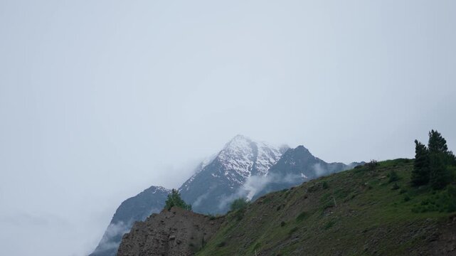 4K Landscape shot of dark clouds covering the snowy Himalayan mountain peaks during the monsoon season as seen near Keylong in Lahaul and Spiti district, Himachal Pradesh, India. 