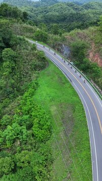 Aerial Adventure Motorcyclists on Winding Road Through Lush Green Forest and Hills, Embracing Nature and Scenic Greenery