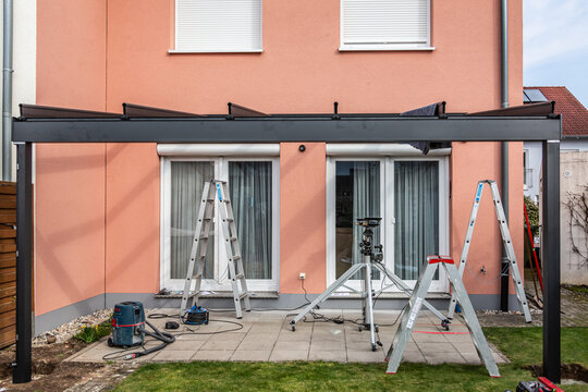 Workers install patio roofing with steel and glass