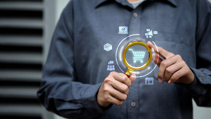 Businessman using magnifying glass to analyze online shopping cart and e-commerce marketing data. © vittaya