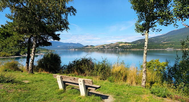 Wooden bench overlooking Lac de Serre-Poncon in French Alps, Alpes-de-Haute-Provence, France, Europe.