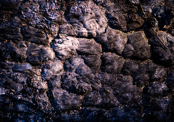 Fototapeta premium Lava rugged texture with crack formation. Lava macro closeup with mineral detail. Lava cooled surface with dark pattern. Lava natural abstract background.