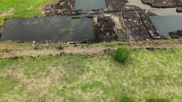 Low angle aerial flyover of ancient sacred bathing pools at Ratu Boko - Detailed view of stone reservoirs and water reflections, Yogyakarta, Indonesia.