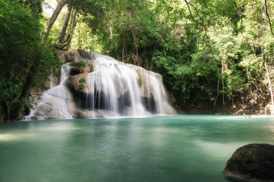 Erawan Waterfall Tier 2 at Wang Macha, renowned travel destination in Kanchanaburi Province, Thailand, waterfall cascades over layered limestone rocks into a crystal clear turquoise pool.