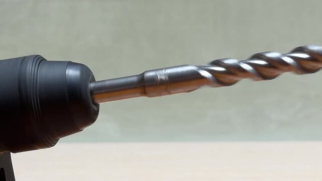 A robust metal drill bit is securely mounted in the chuck of a power tool. The sharp, spiraled grooves and cold steel evoke a sense of readiness and industrial precision.