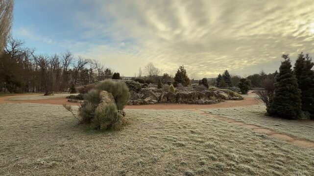 Frost-covered grass and evergreen trees sparkle under a dramatic, cloudy sky. This peaceful winter scene in Salgirka Park evokes a sense of quiet wonder and crisp, morning serenity.
