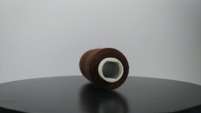 sewing thread lying sideways and rotating on clean surface.