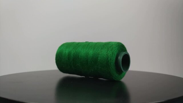 sewing thread lying sideways and rotating on clean surface.