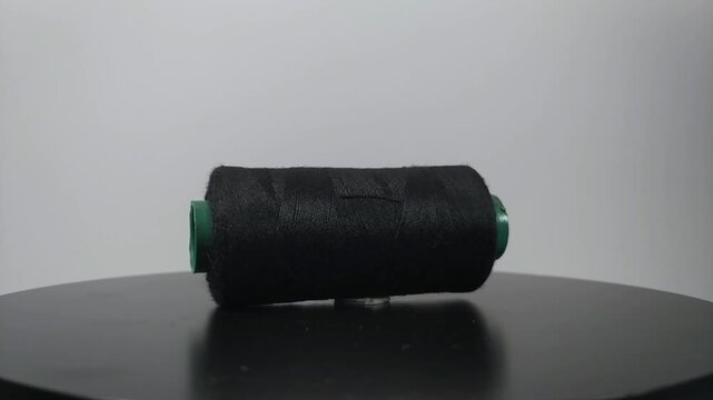 sewing thread lying sideways and rotating on clean surface.