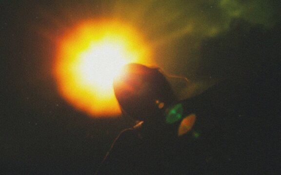 Silhouette of person against dramatic sunset with vibrant lens flare and moody atmosphere