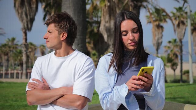 A couple sits on a bench, absorbed in their smartphones, showcasing a disconnect in their relationship, as they focus on their devices instead of each other, reflecting modern communication challenges