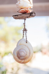 Close up of a handmade wind chime featuring a large spiral seashell