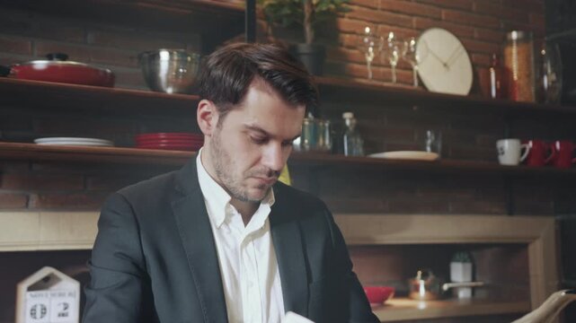Writer ponders ideas in cozy setting, Person analyzes news articles in intimate industrial kitchen environment