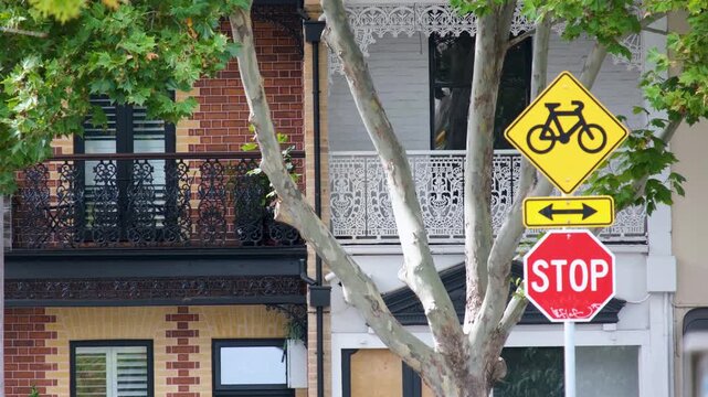 Historic terrace house balconies a residential street in west Melbourne, Australia, against a bicycle crossing warning sign and stop sign. Heritage architecture in an inner-city neighborhood.