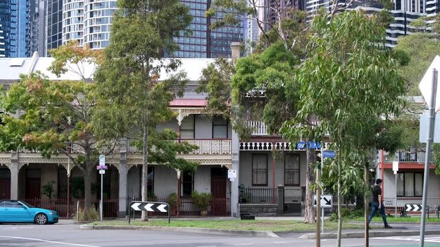 Historic terrace houses with ornate verandas in West Melbourne, Australia, against modern high-rise apartment buildings. Urban street, heritage architecture, inner-city living, old and new