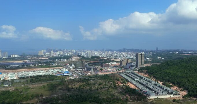 Wide forward aerial view of Sihanoukville's urban expansion, revealing an amusement park under construction, a residential villa compound, and a dense city skyline.