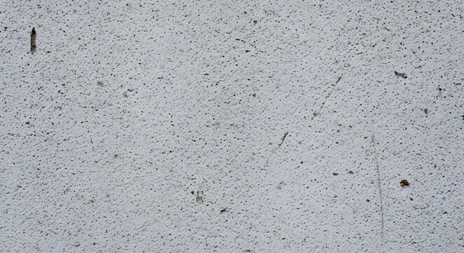 A close up view of a rough light gray concrete wall surface with a textured and porous appearance