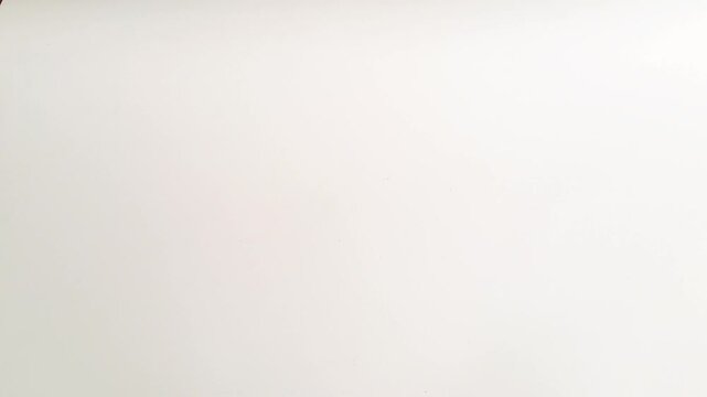 Horizontal shot of an Asian man's hands spinning a silver coin on a white minimalist background. This footage captures the concept of probability. PAMEKASAN, INDONESIA - APRIL 1, 2026
