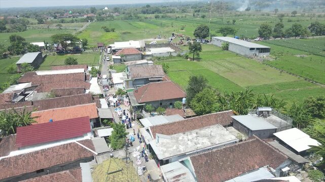 Aerial view of a local parade or funeral procession walking through a rural Indonesian village.