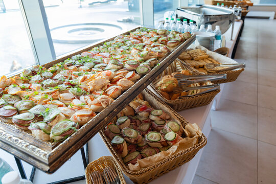 Catering with meats, fruits, cheeses and sandwiches. An assortment of cold cuts and canapes on wooden skewers