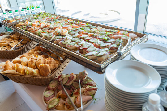 Catering with meats, fruits, cheeses and sandwiches. An assortment of cold cuts and canapes on wooden skewers