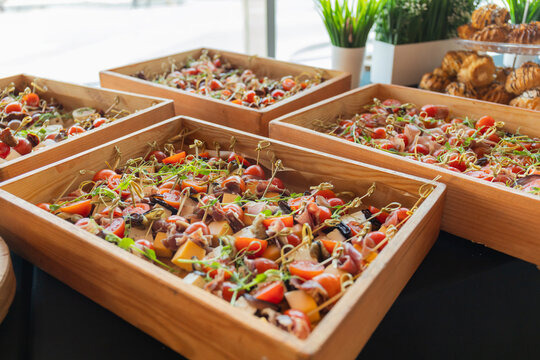 Catering with meats, fruits, cheeses and sandwiches. An assortment of cold cuts and canapes on wooden skewers